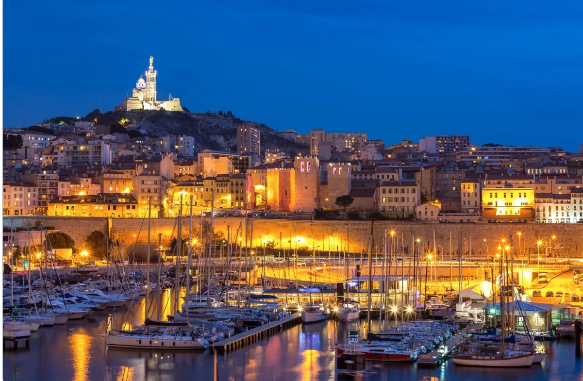 Vue nocturne du Vieux-Port de Marseille « Vue panoramique nocturne du Vieux-Port de Marseille avec Notre-Dame de la Garde éclairée. »