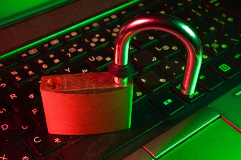 Cadenas ouvert posé sur un clavier éclairé en rouge et vert, symbolisant la sécurité informatique.